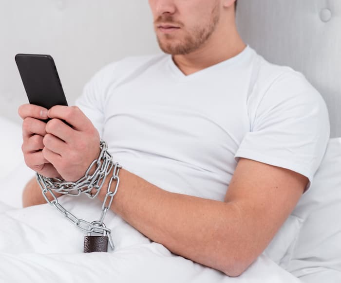 man-checking-his-phone-while-he-is-tied-up-with-chains (1) (1)